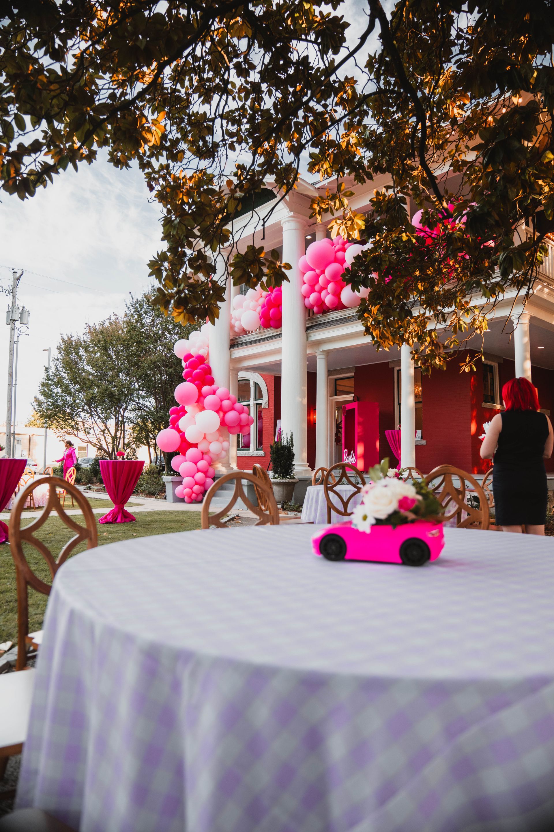 A table with a pink car on it and balloons on it.