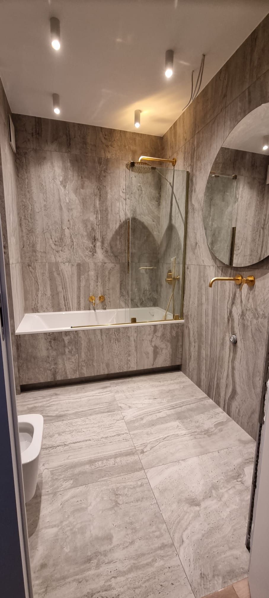 Modern bathroom with large format tile and gold fixtures