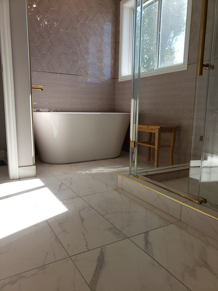 Bright Sherwood Park bathroom with freestanding tub and stylish marble-look tiles by XMP Construction.