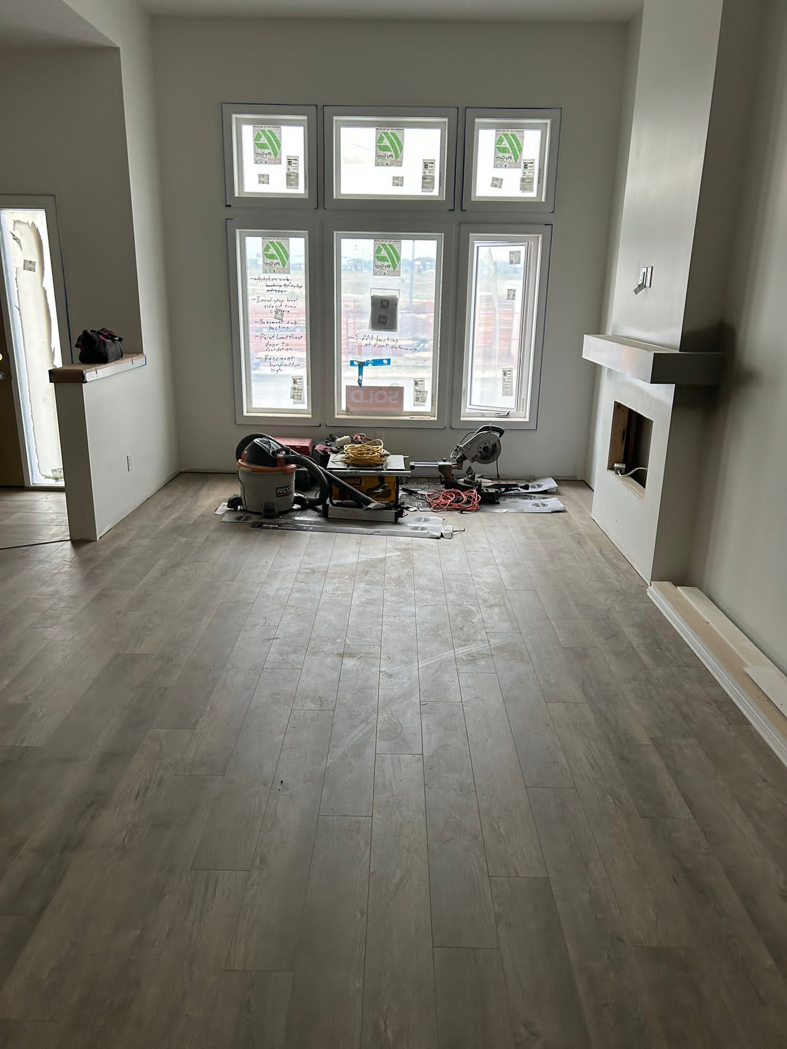 Light wood-look luxury vinyl plank flooring installation in a Sherwood Park living room by XMP Construction.