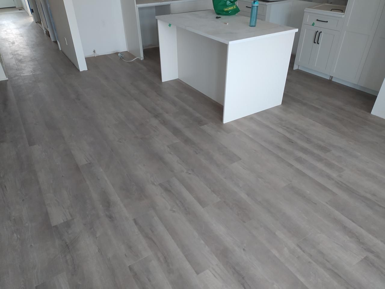 Modern Sherwood Park kitchen with light grey LVP flooring and a white waterfall edge island by XMP Construction.