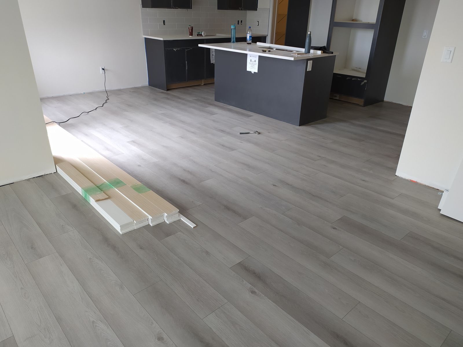 Installation of light grey luxury vinyl plank flooring in a Sherwood Park kitchen by XMP Construction.
