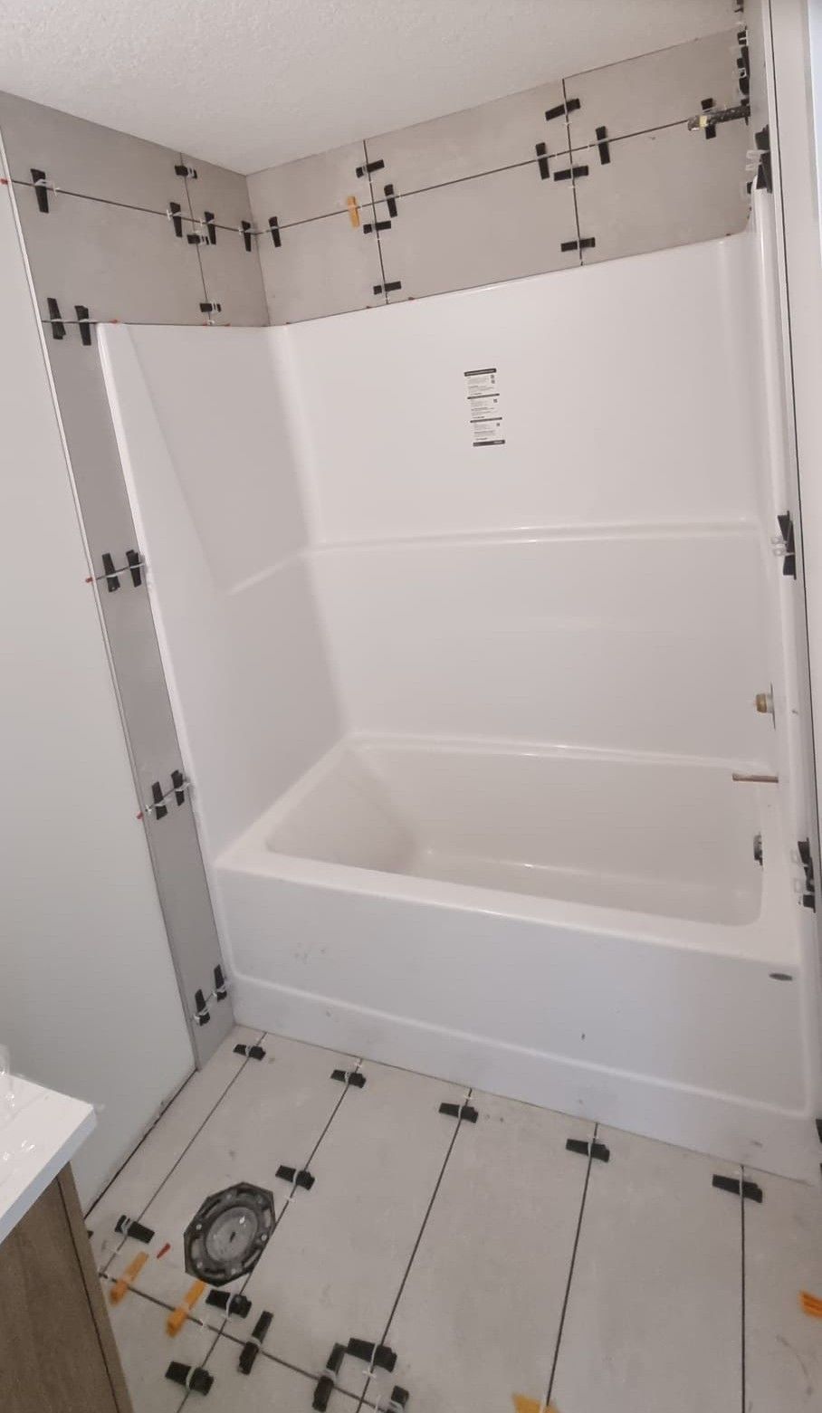 Installation of large light grey tiles around a bathtub in a Sherwood Park bathroom by XMP Construction.