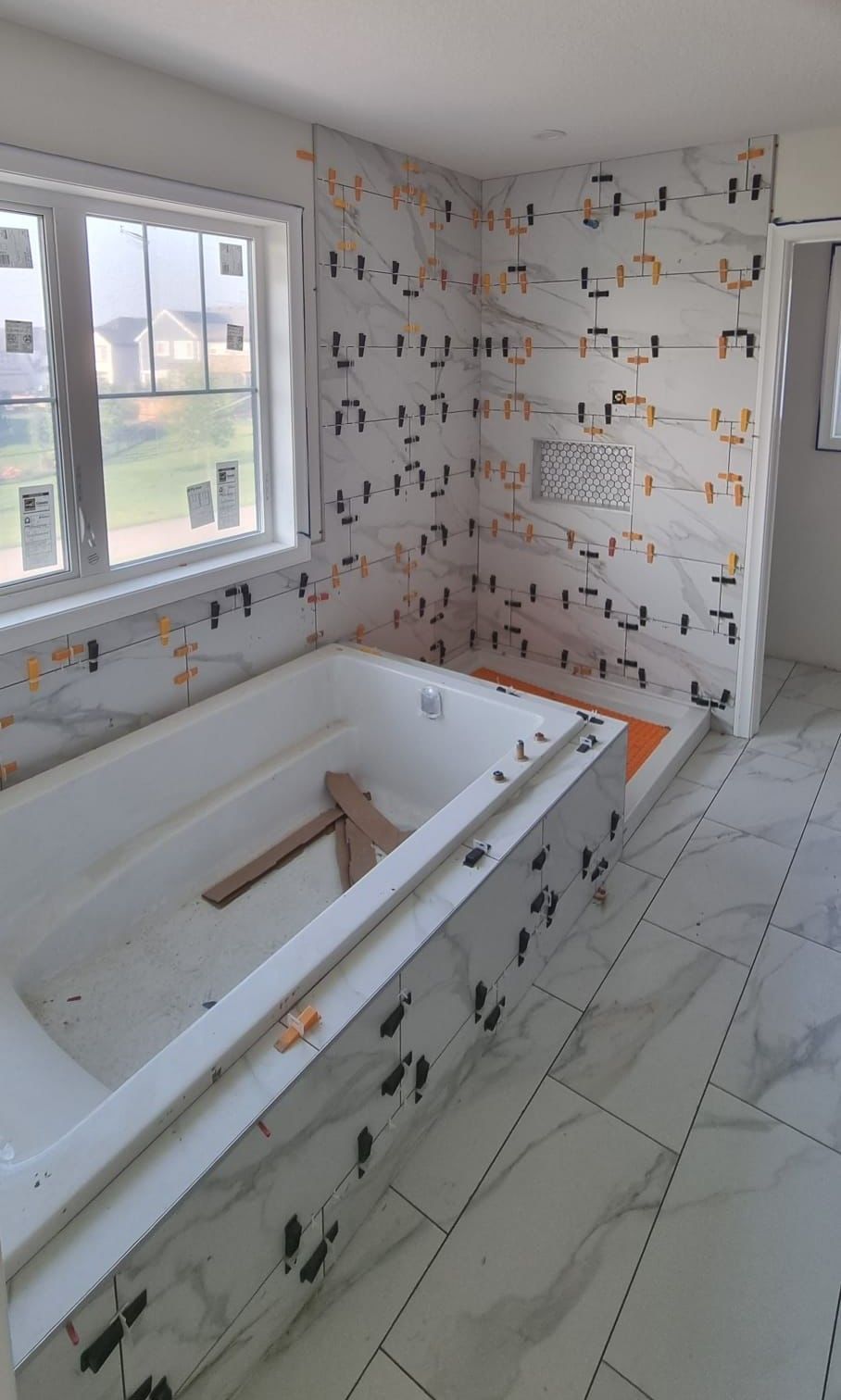 Installation of large white marble-look tiles in a Sherwood Park bathroom by XMP Construction.