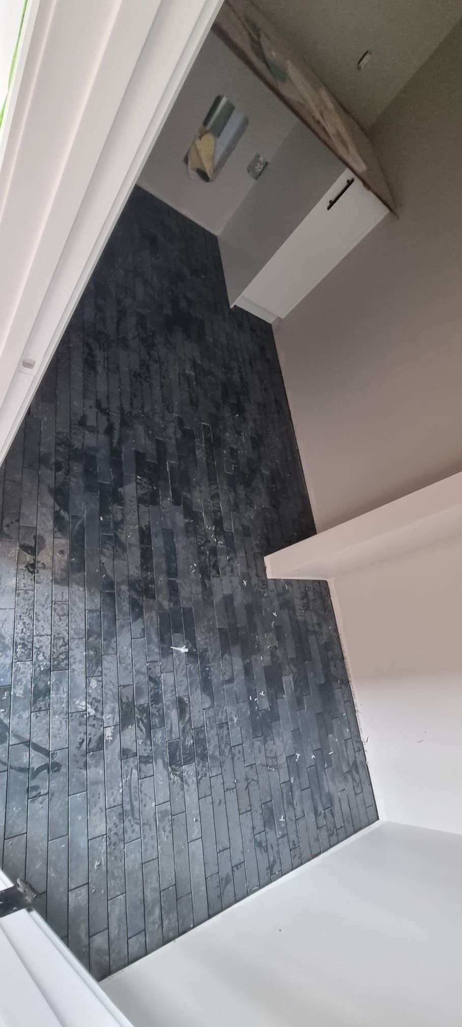 Installation of dark, vertically stacked, glossy tiles in a Sherwood Park room by XMP Construction.