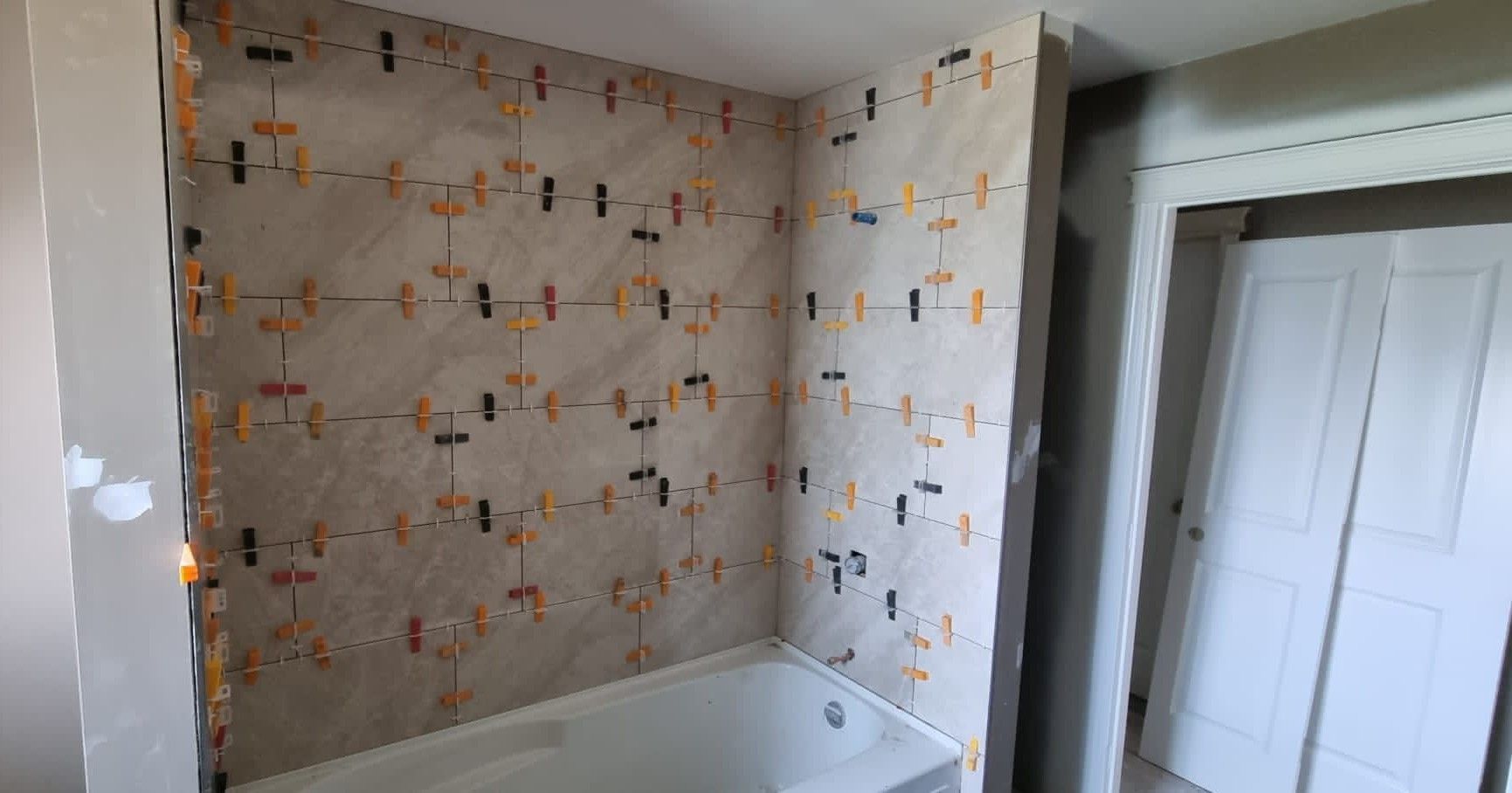 Installation of large light beige tiles in a Sherwood Park bathtub surround by XMP Construction.