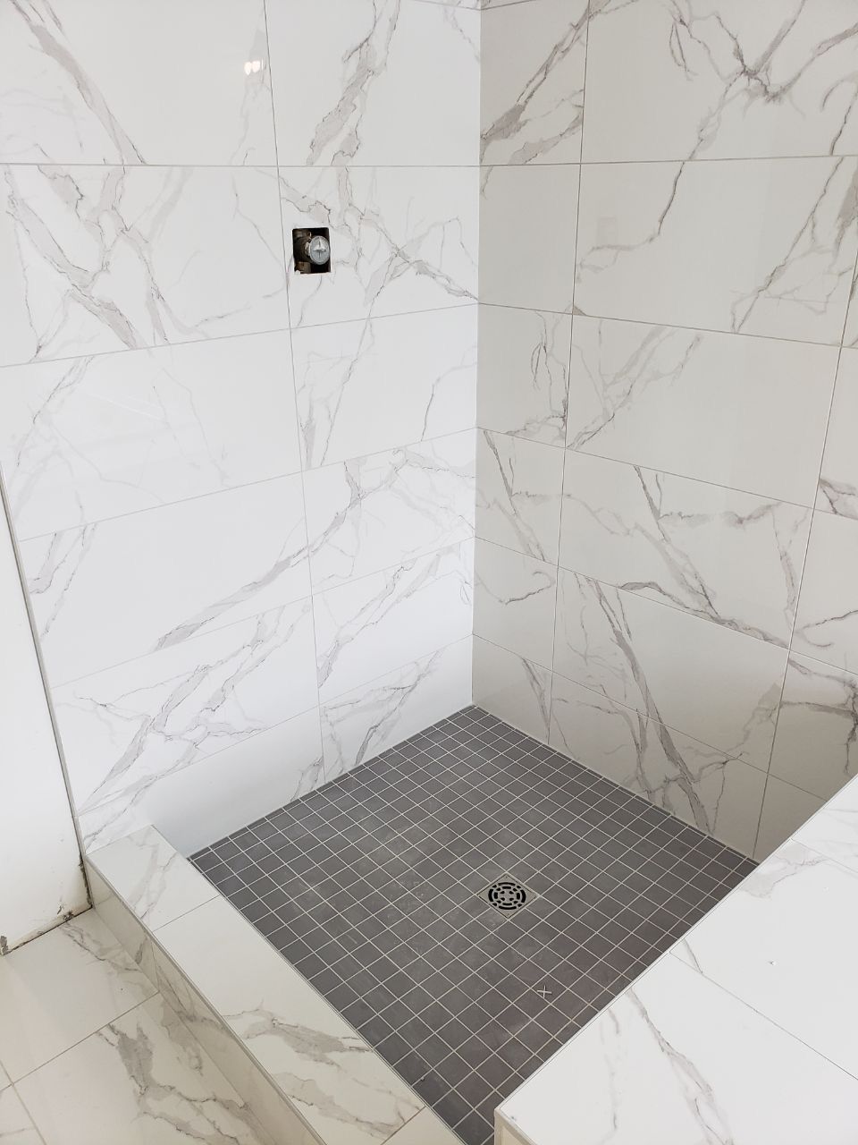 Modern Sherwood Park shower with large white marble-look wall tiles and a contrasting grey tiled floor by XMP Construction.