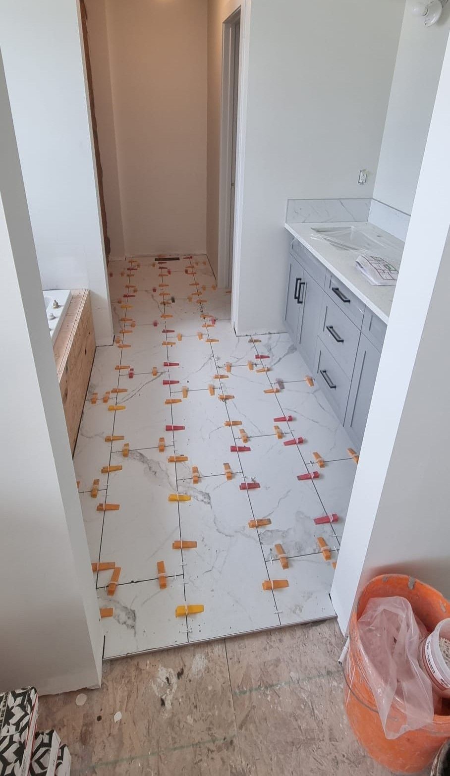 Installation of large white marble-look porcelain tiles in a Sherwood Park bathroom by XMP Construction.