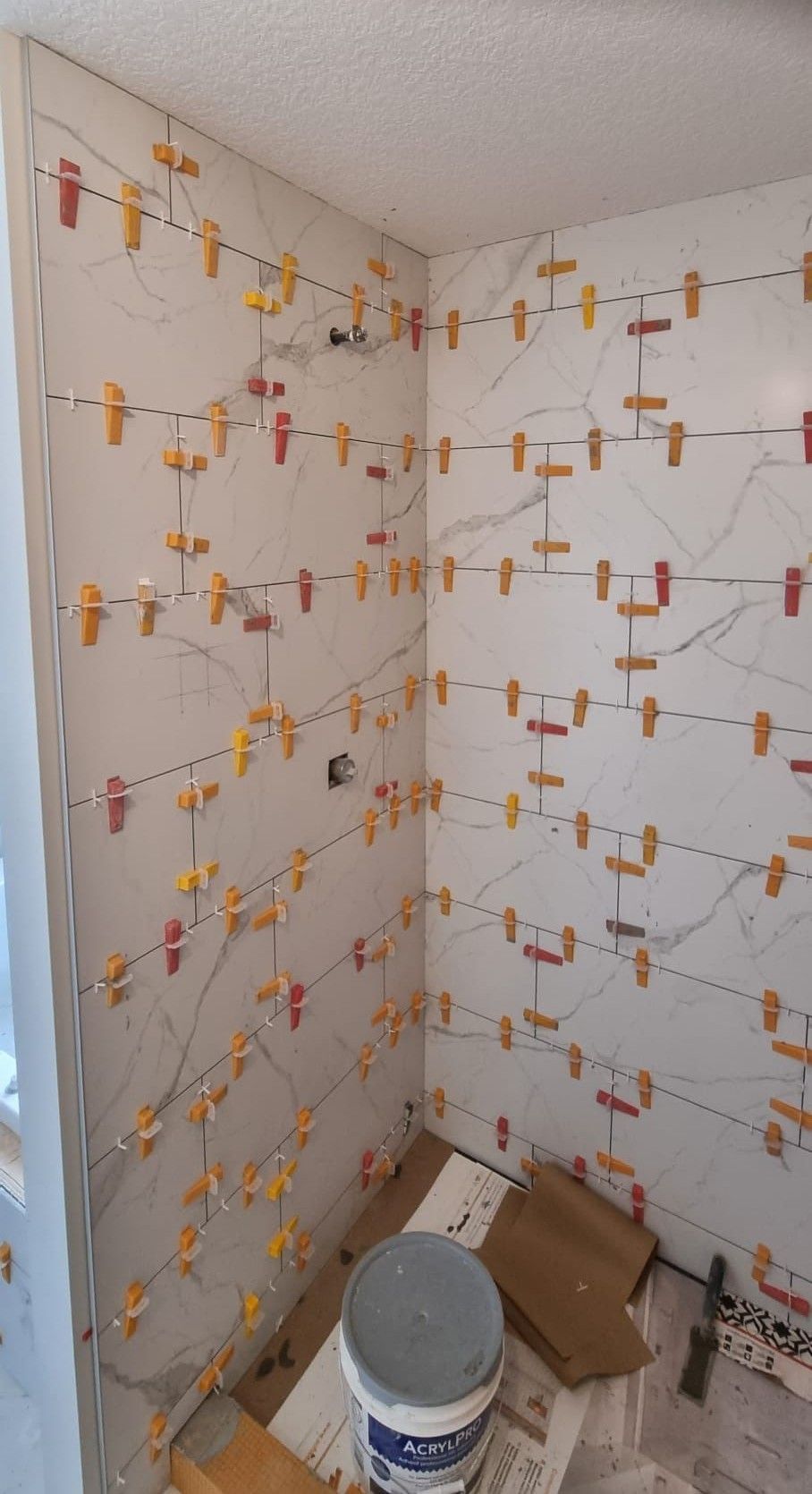 Installation of large white marble-look tiles in a Sherwood Park shower by XMP Construction.