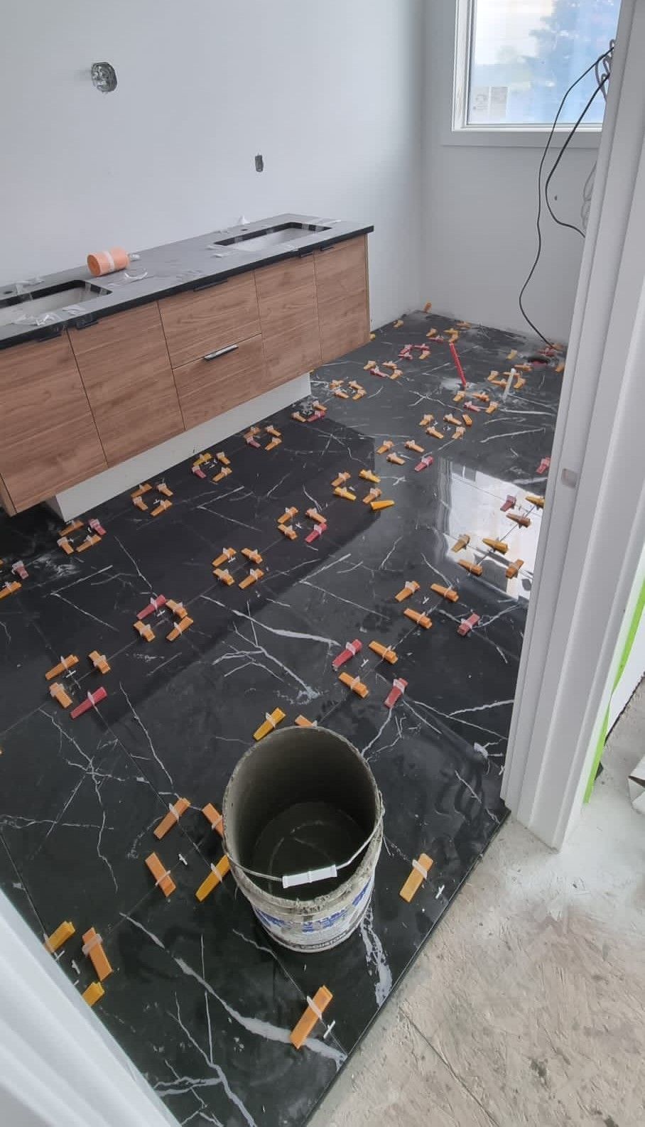 Installation of epoxy black marble-look floor tiles in a Sherwood Park bathroom by XMP Construction.