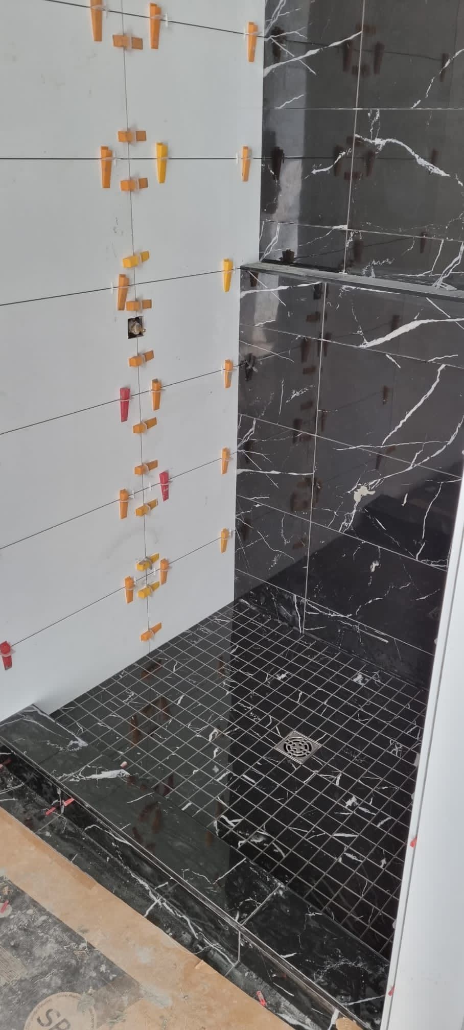 Installation of contrasting black marble-look and white vertical stack tiles in a Sherwood Park shower by XMP Construction.