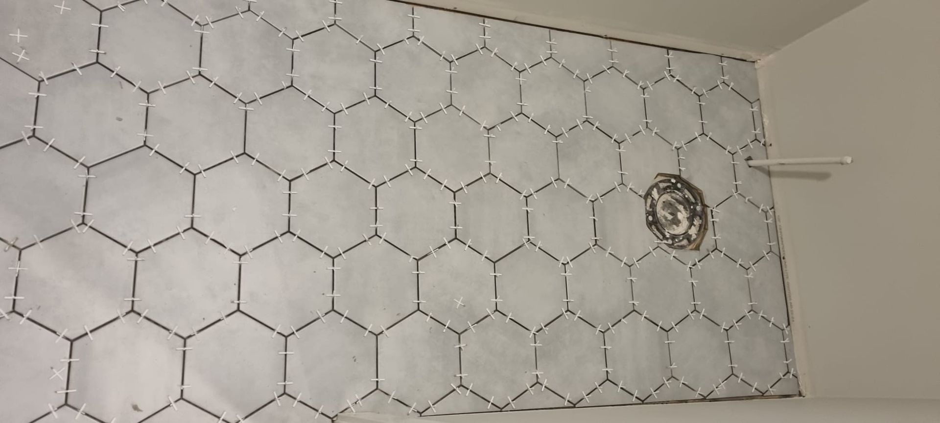 Installation of light grey hexagon wall tiles in a Sherwood Park shower by XMP Construction.