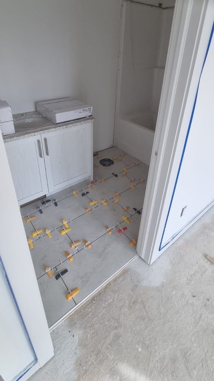Installation of large light grey floor tiles in a Sherwood Park bathroom by XMP Construction.
