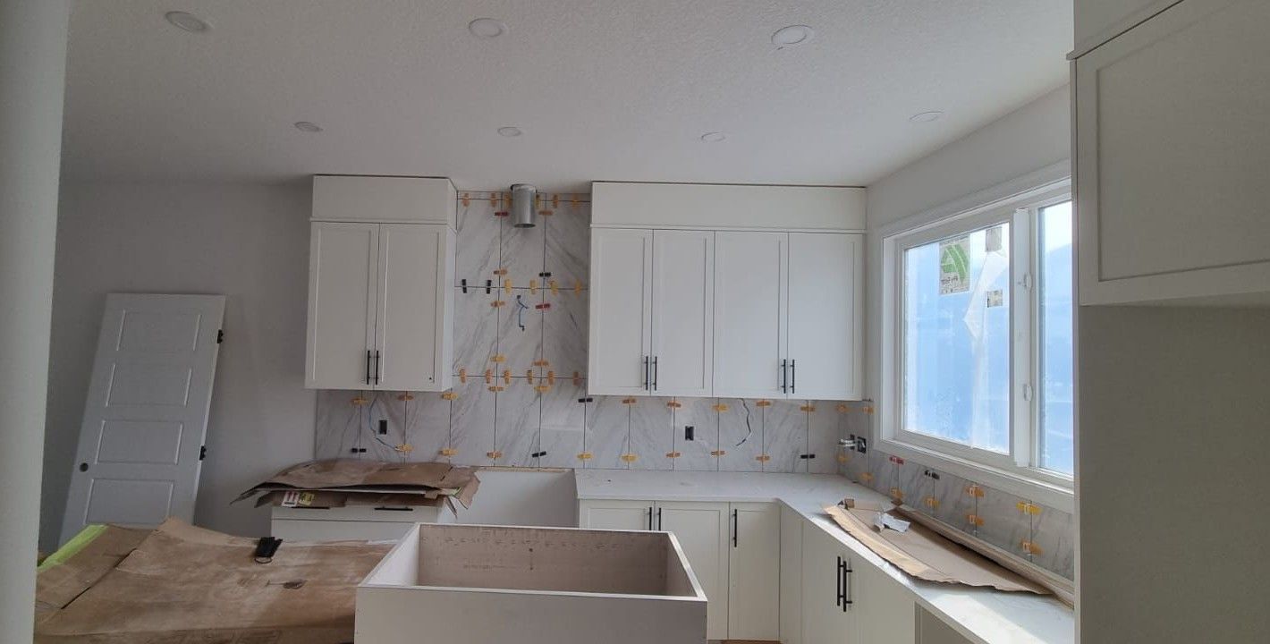Installation of elegant white marble-look backsplash tiles in a Sherwood Park kitchen with white cabinets by XMP Construction