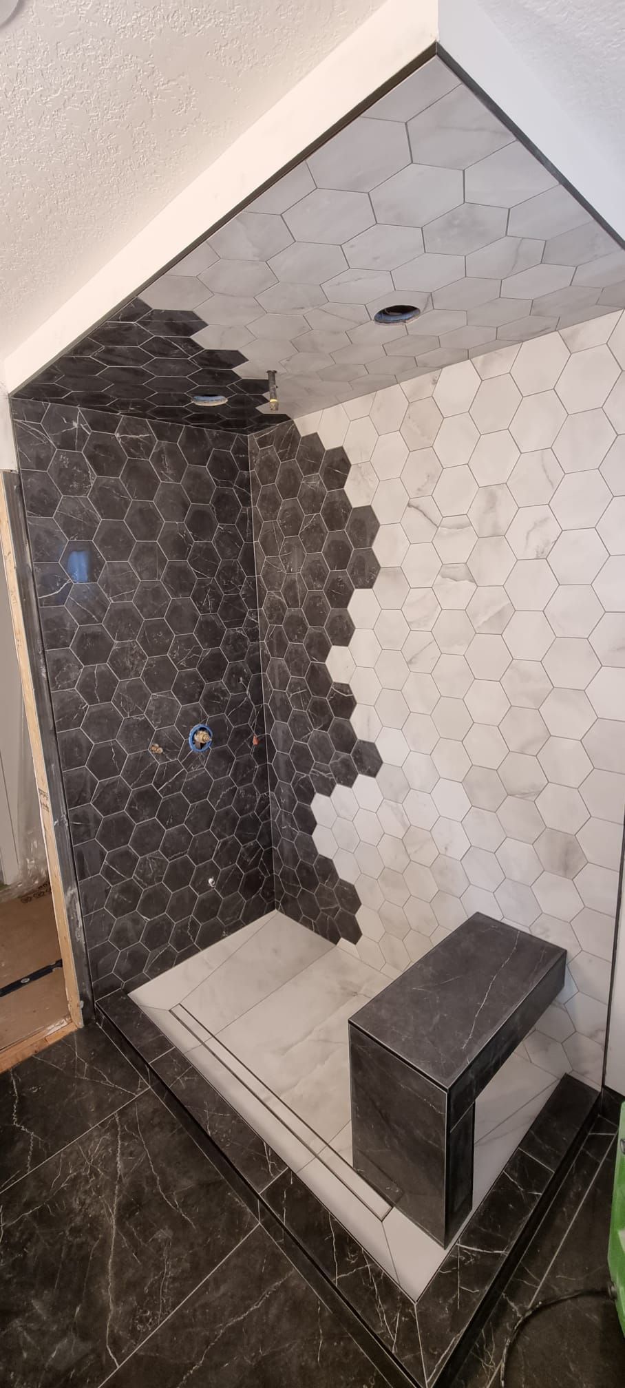 Modern shower with contrasting black and white hexagon tiles in a Sherwood Park bathroom by XMP Construction.