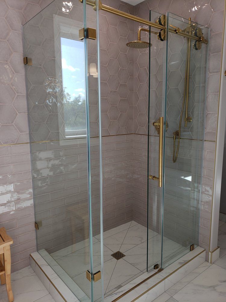 Glass shower enclosure with hexagon and subway tiles, featuring gold hardware in a Sherwood Park bathroom by XMP Construction