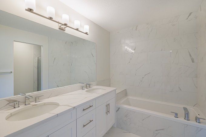 Bright Sherwood Park bathroom with elegant white marble-look tiles and double vanity by XMP Construction.