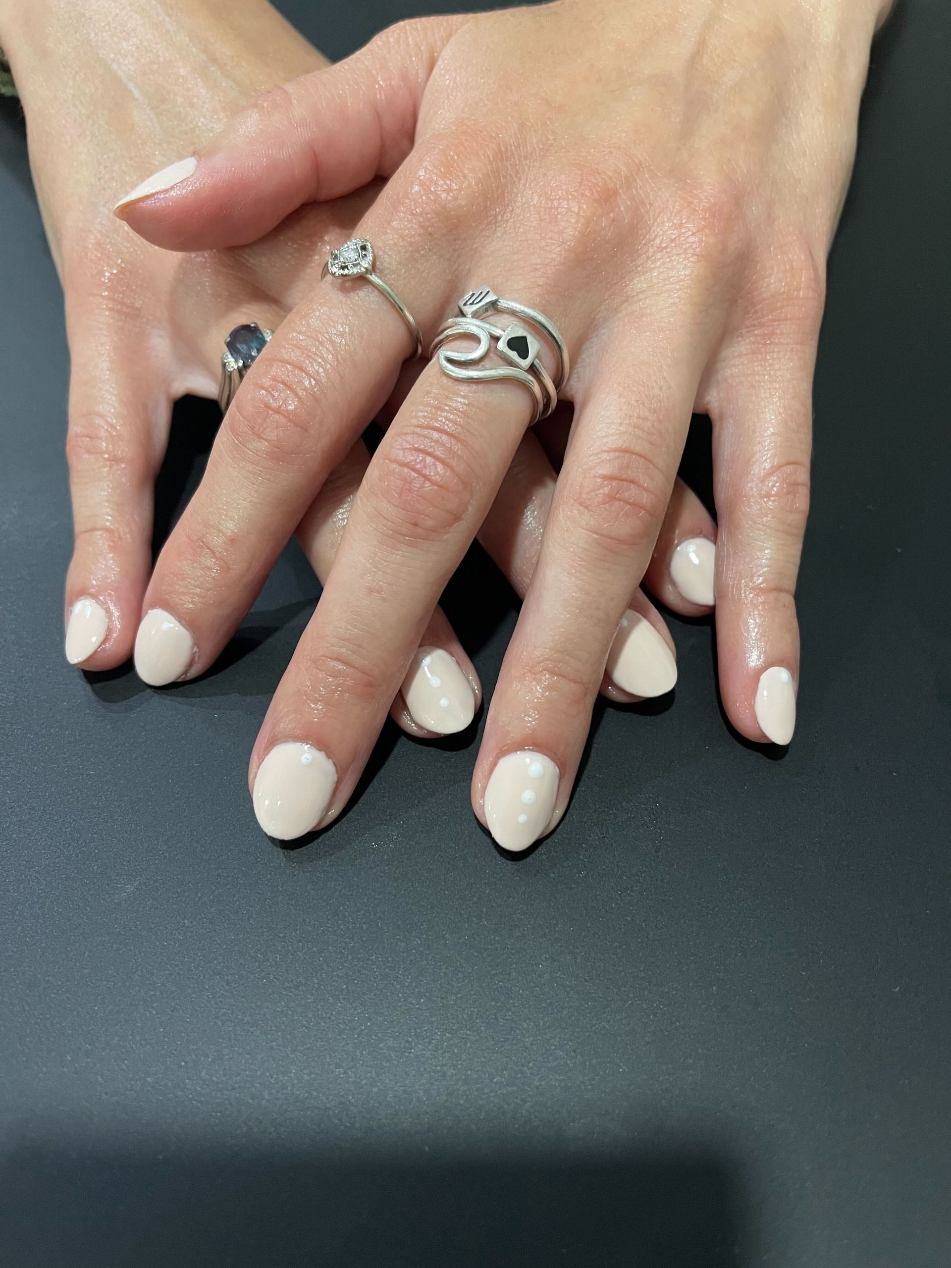 a woman 's hand with three rings on it, neutral manicure