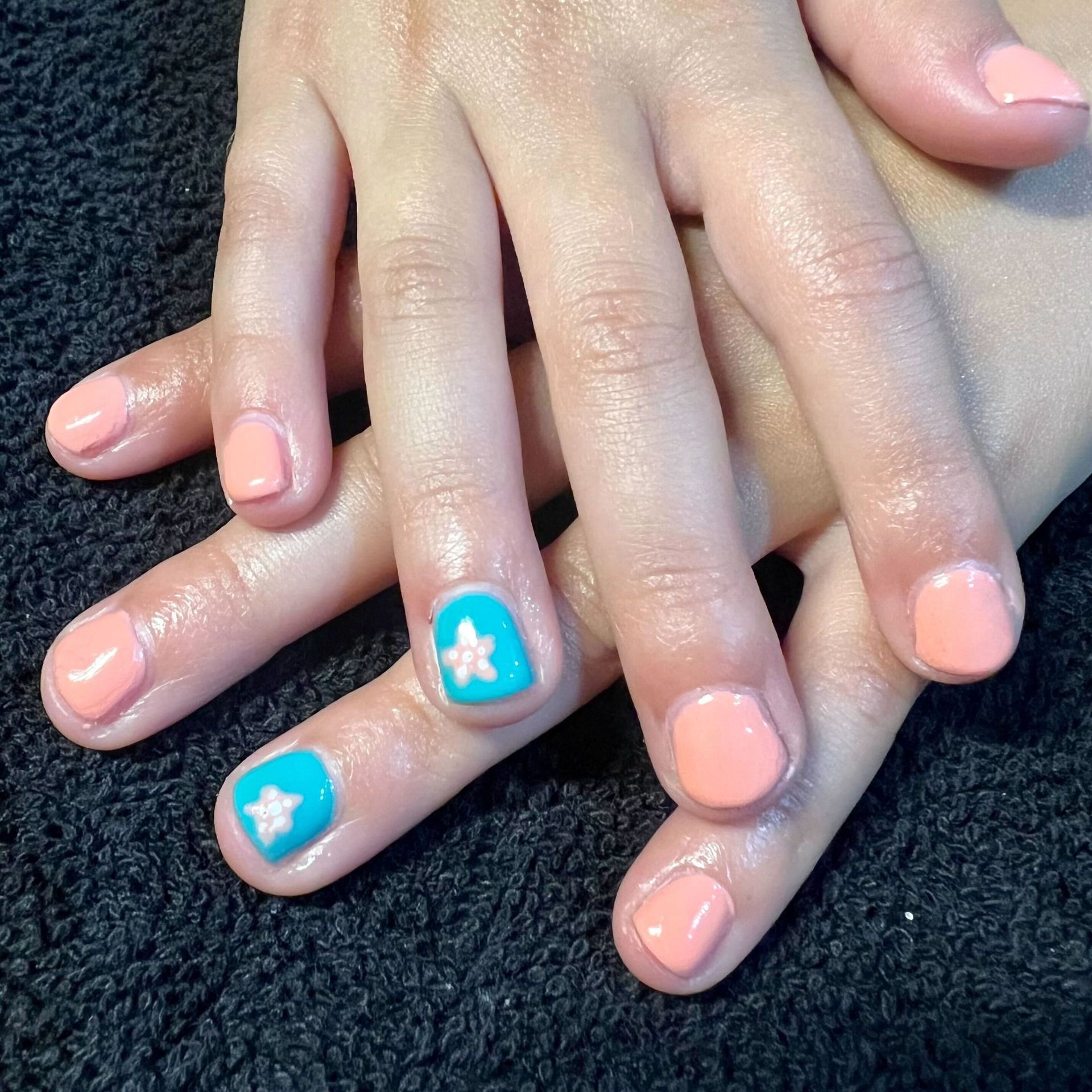 a close up of a person 's nails with a blue star on the ring finger