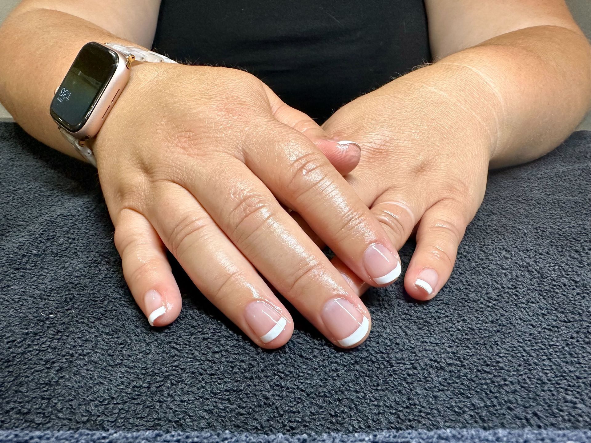 a woman has her hands folded and french manicure
