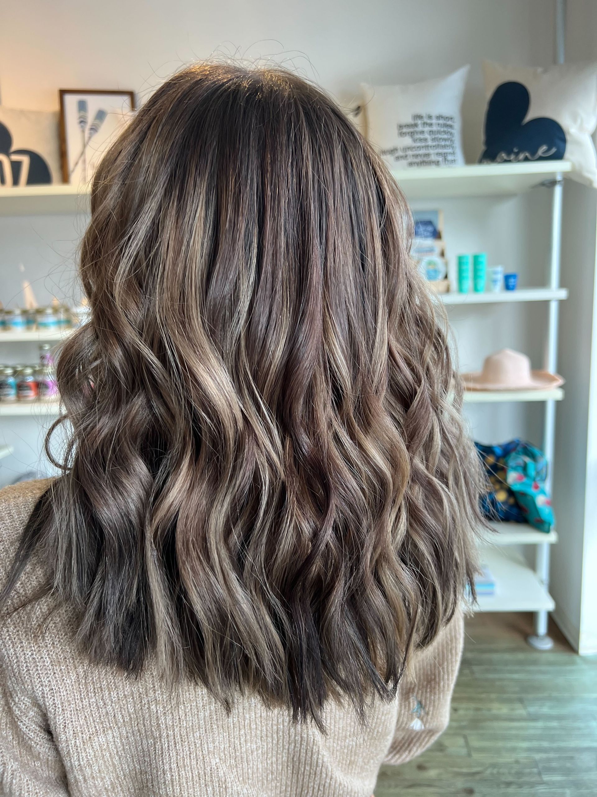 a woman wearing a brown sweater has long wavy hair
