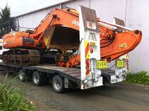A large orange excavator is sitting on top of a flatbed truck.