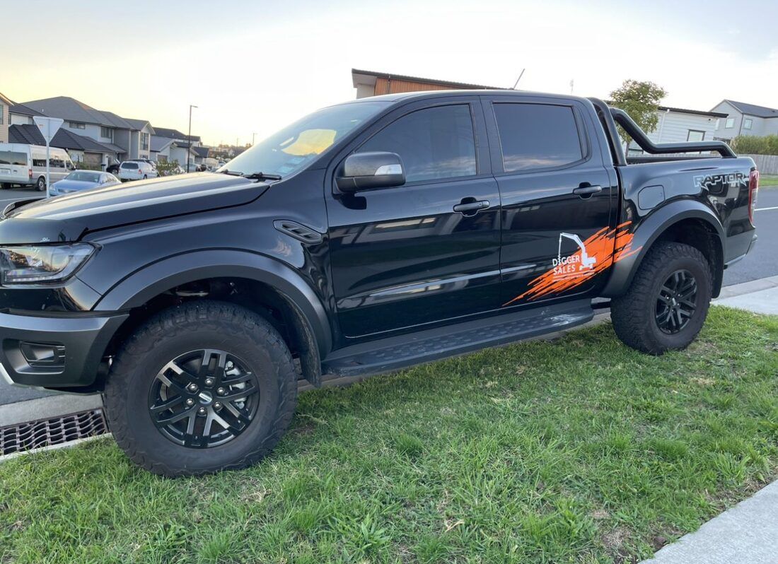 A black pickup truck is parked in the grass on the side of the road.