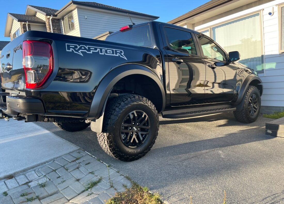 A black raptor truck is parked in front of a house.