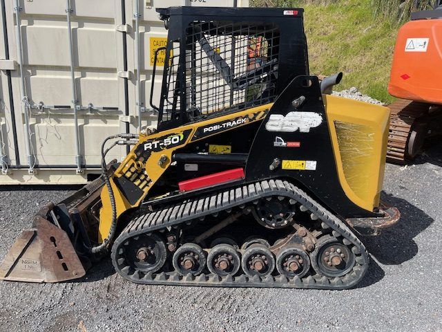 A yellow and black tractor is parked next to a white container.
