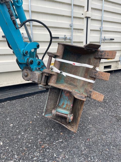 A blue excavator with a bucket attached to it is parked on the side of the road.