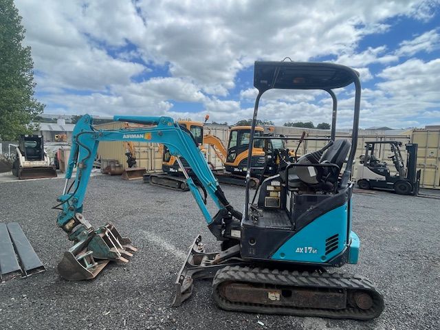 A small blue excavator is parked in a parking lot.