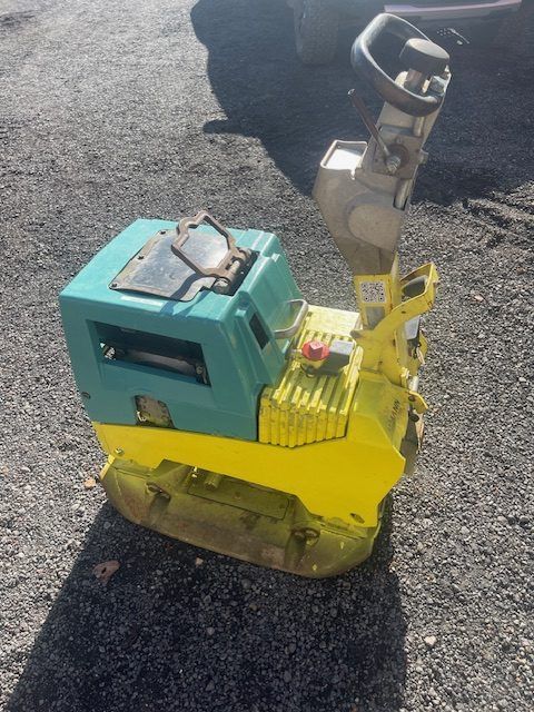 A small yellow and blue machine is sitting on the ground.