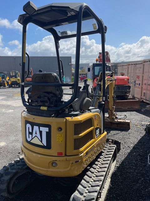 Yellow CAT mini excavator on tracks at a gravel construction site