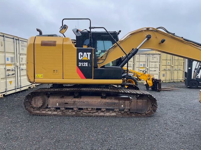A yellow cat excavator is parked in a gravel lot.