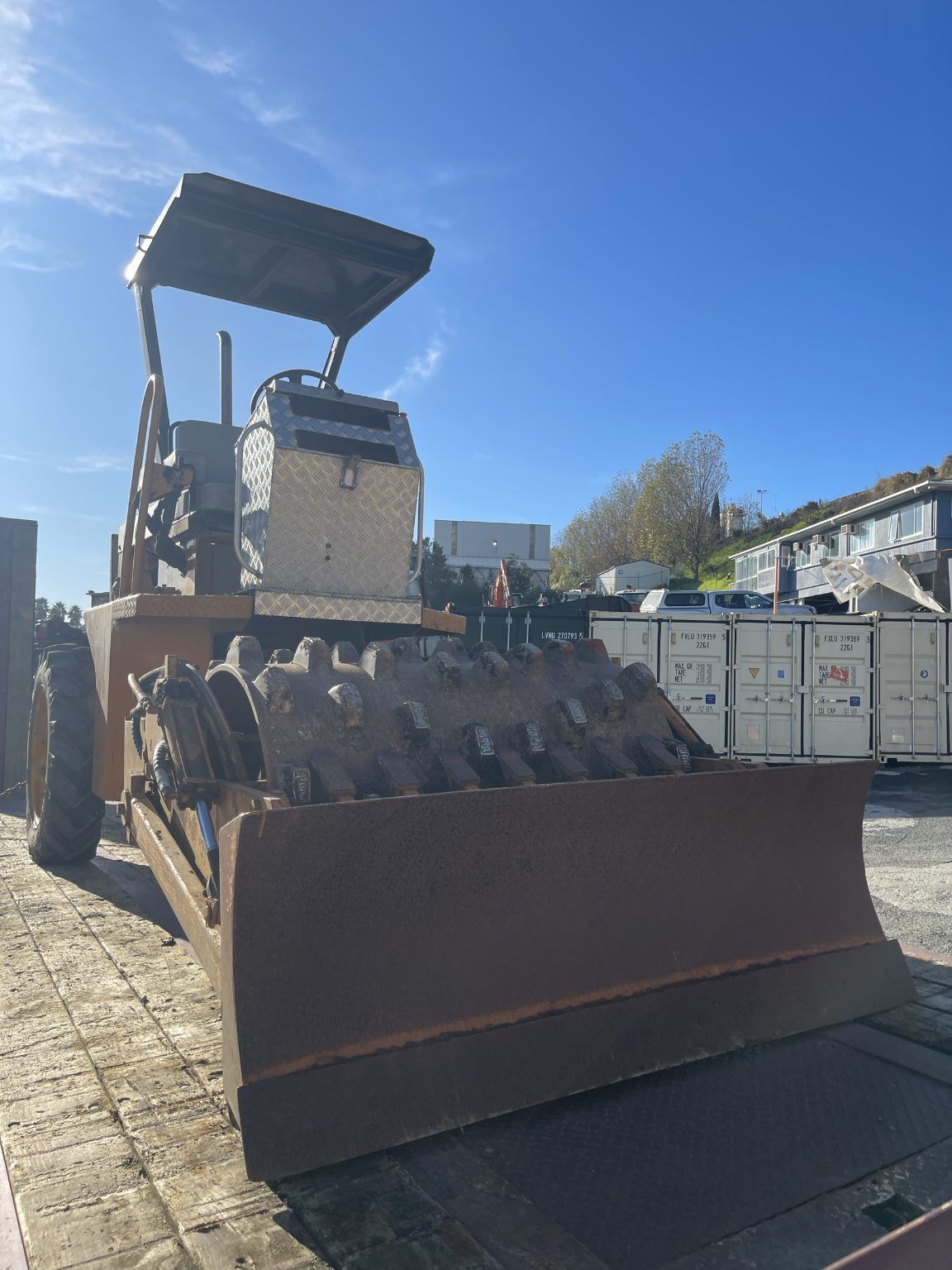 A bulldozer is parked in a parking lot on a sunny day.