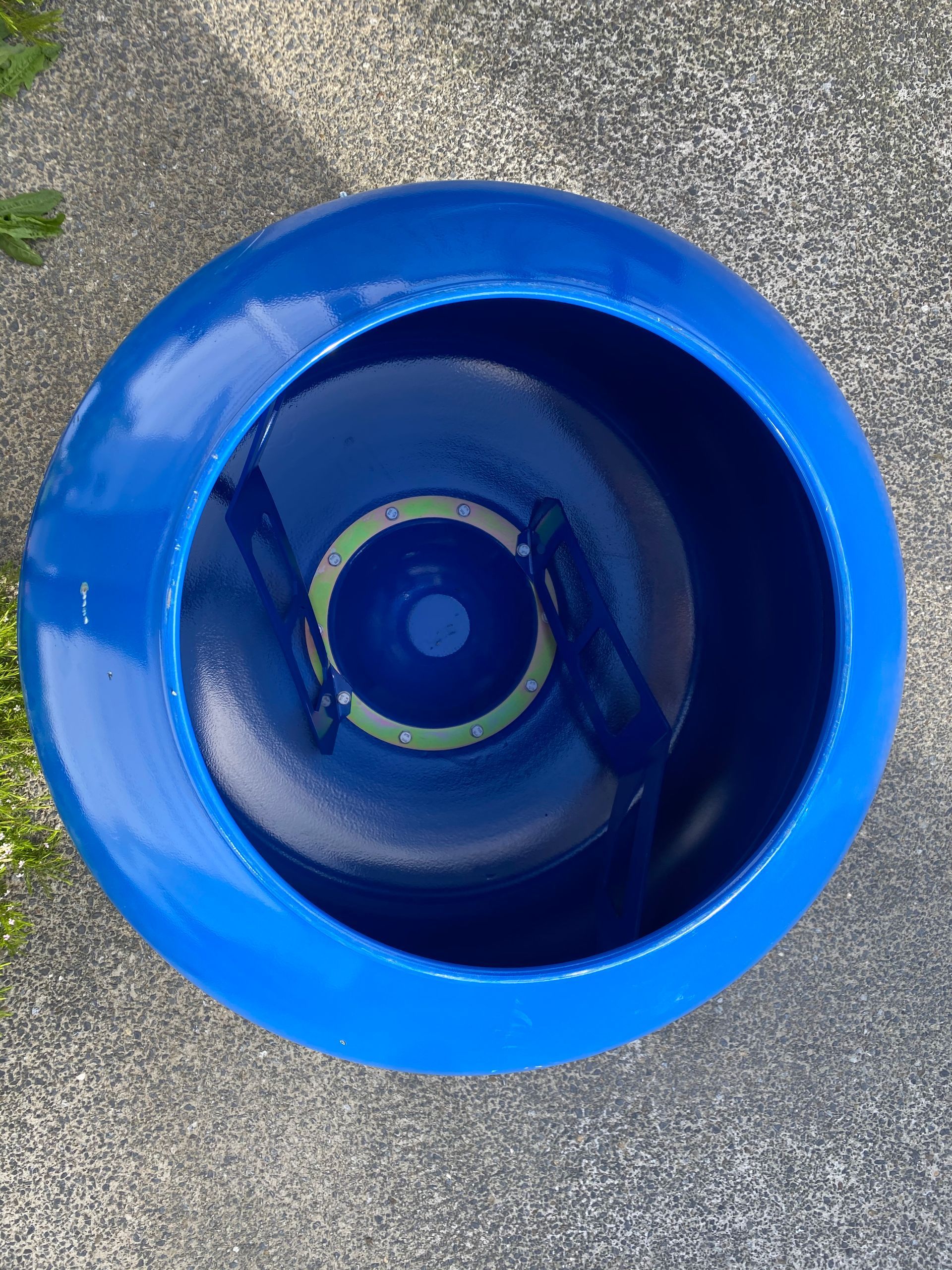 A blue bowl is sitting on a concrete surface.