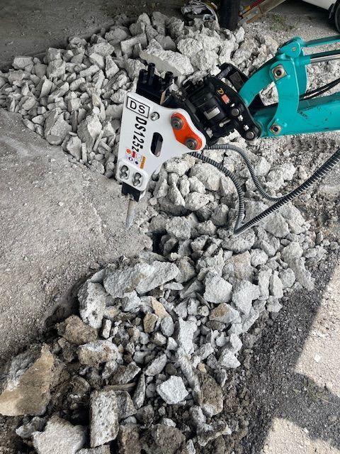 A machine is breaking up a pile of rocks on the ground.