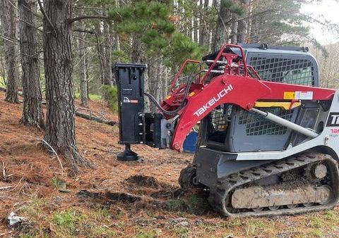 A small bulldozer is sitting in the middle of a forest.