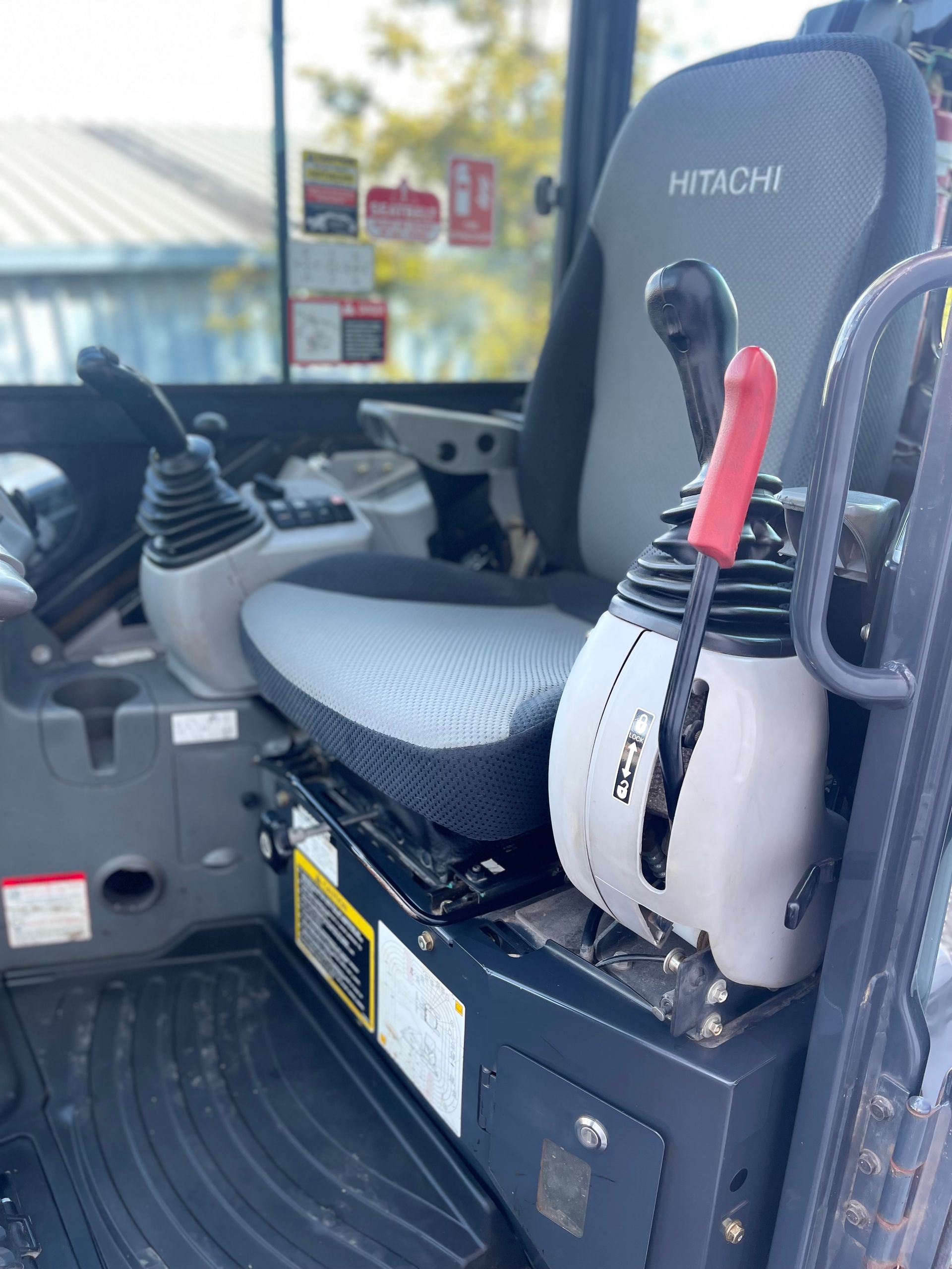 The inside of a hitachi tractor with a seat and controls