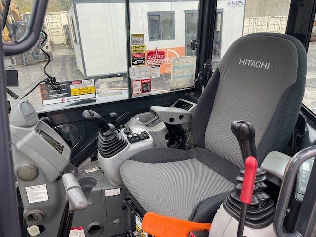 The inside of a hitachi excavator with a gray seat.