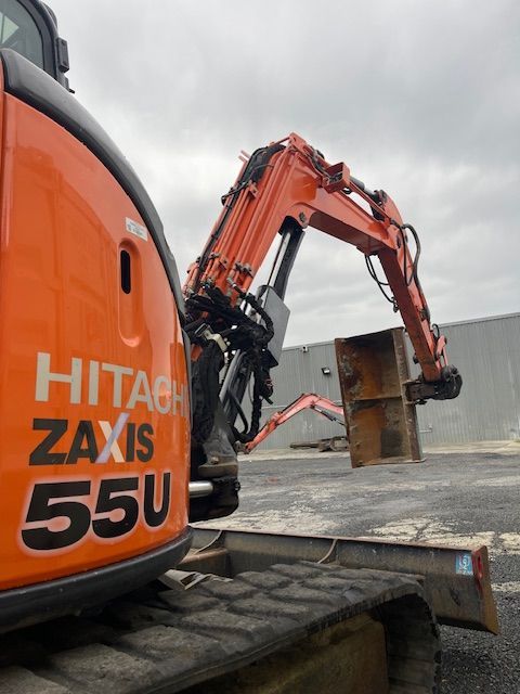 An orange hitachi excavator is parked in a parking lot