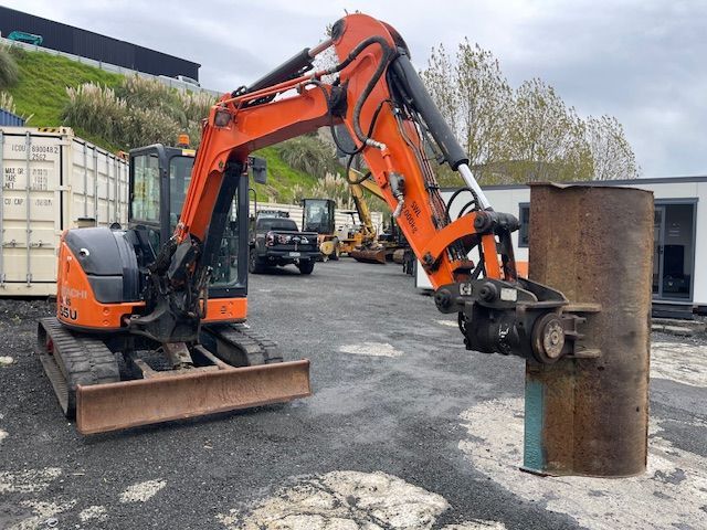 A small orange excavator is parked in a parking lot.