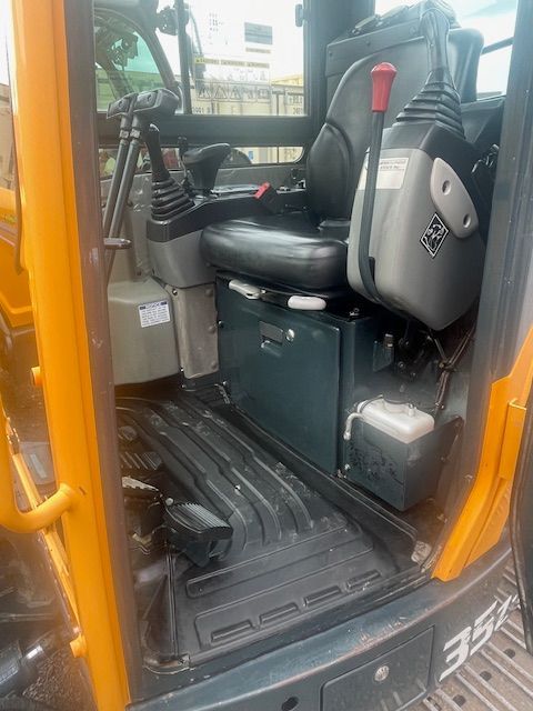 The inside of a yellow excavator with a black seat.
