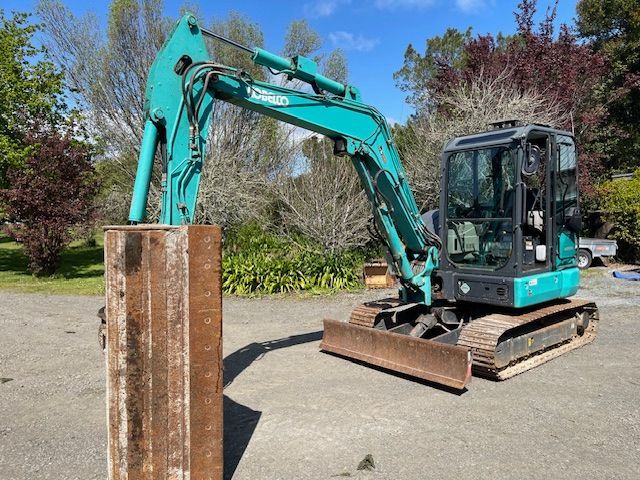 A green and black excavator is sitting on top of a metal pole.