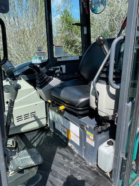 The inside of an excavator with a black seat
