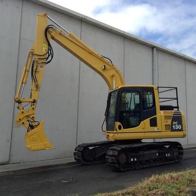 A yellow excavator is parked in front of a concrete wall.
