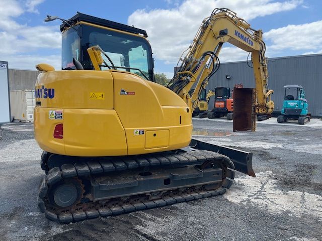 Yellow excavator on a gravel lot with another excavator in the background.
