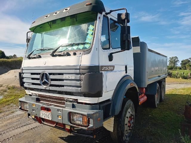 White Mercedes dump truck on a dirt road in a rural field