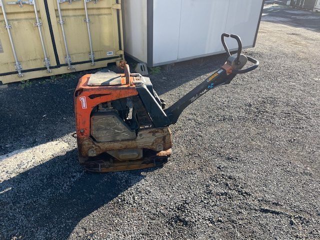 A machine is sitting on the ground in a parking lot.