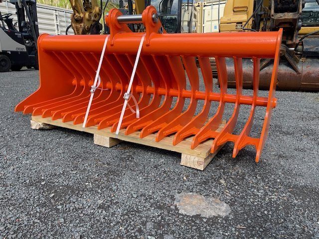 A black rake is sitting on top of a wooden pallet on the ground.